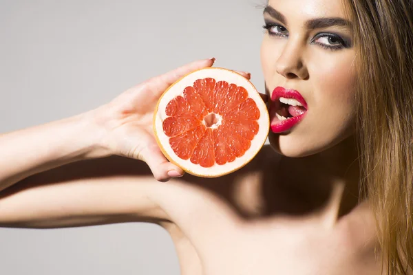 Glamour flicka håller grapefrukt och tuoching honom med läppar — Stockfoto
