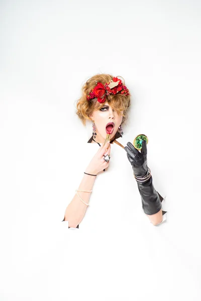 Woman with red flowers in hair doing make-up — Stock Photo, Image