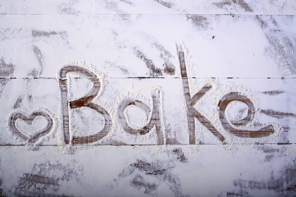 Wooden table top with text on flour — Stock Photo, Image