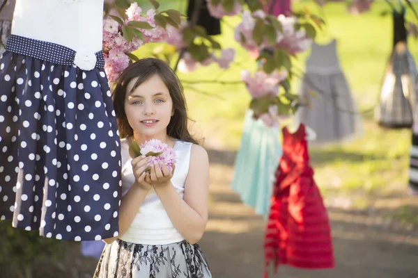 Niña entre vestidos en el árbol — Foto de Stock