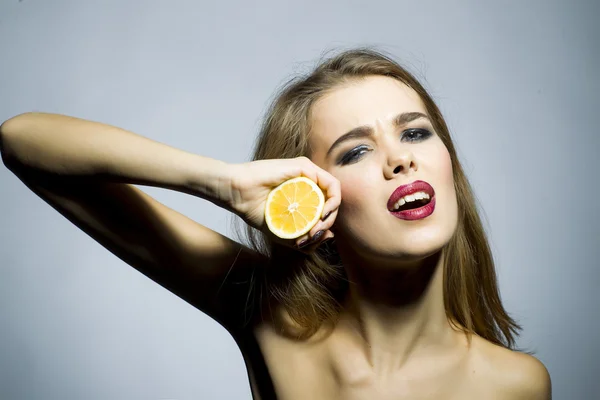 Söt blond flicka stående med orange — Stockfoto