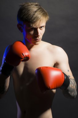 Genç seksi kaslı çocuk ciddi yüzüne kırmızı boks eldivenleri ile
