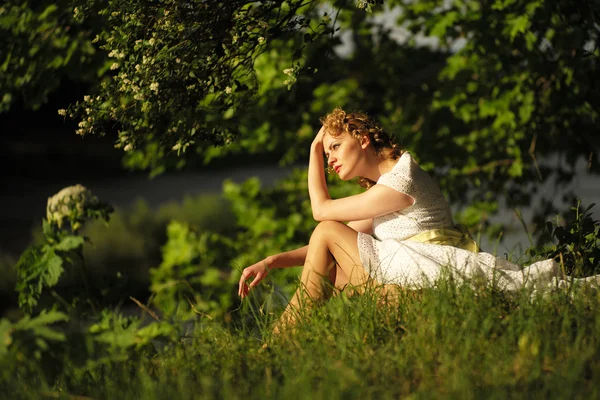 Женщина в платье сидит на траве — стоковое фото