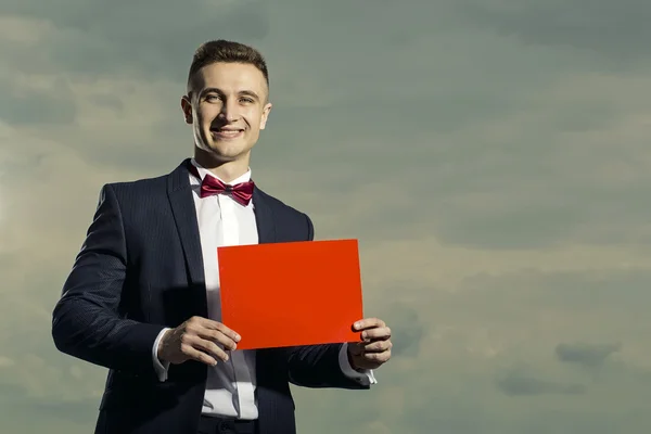 Homem sorridente de terno com folha de papel — Fotografia de Stock