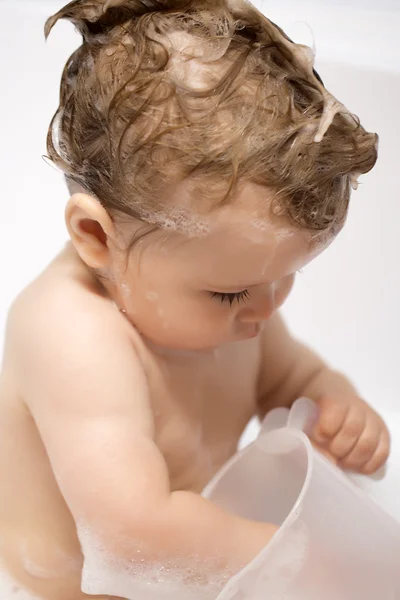 Младенец играет с ковшом в ванне — стоковое фото