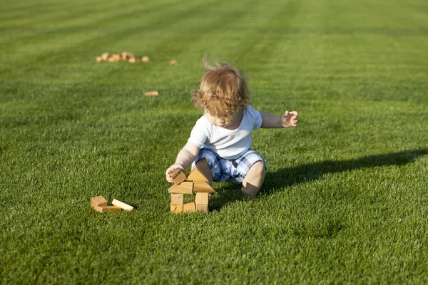 Little baby boy builds a wooden house — Stock Photo, Image