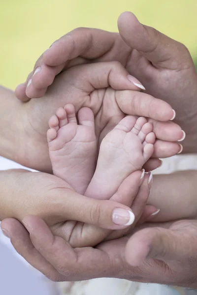 Happy young family holding bare feet of little tiny baby — ストック写真