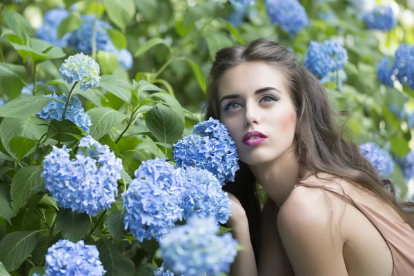 Gyönyörű nő és kék virágok portréja — Stock Fotó