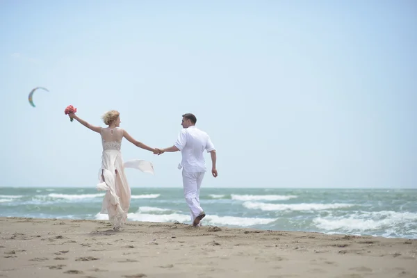 Pareja de boda juguetona en la playa — Foto de Stock