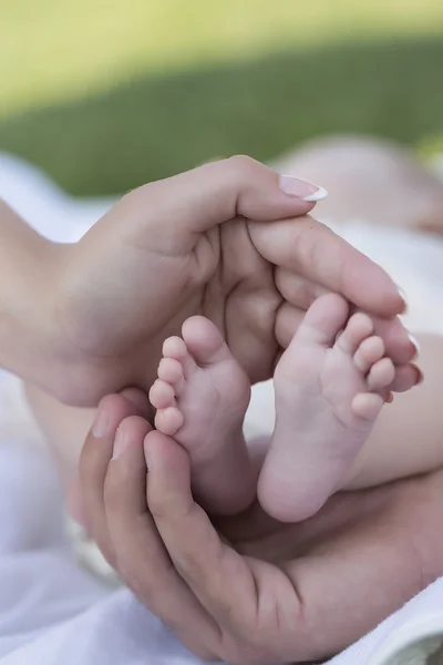 Happy young family of parents holding bare feet of little tiny baby — ストック写真