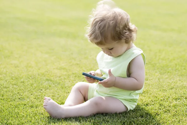 Little boy on grass with phone