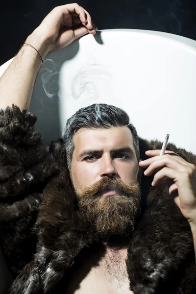 Confident man smoking in bathtub