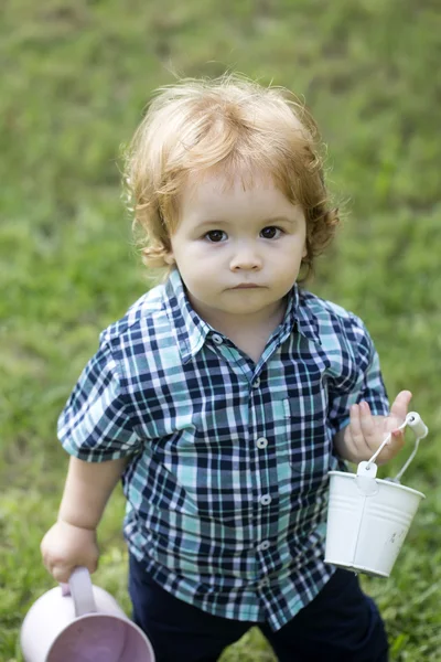 Small boy with watering-can and bucket