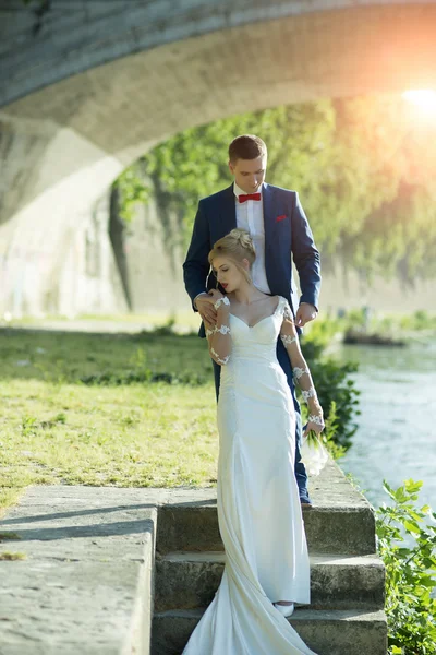 Hermosa pareja de boda bajo puente — Foto de Stock