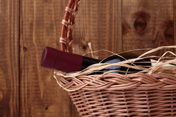 Bottle of wine with straw in basket — Stock Photo, Image