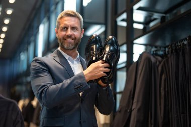 Moda mağazasındaki bir müşteri farklı ayakkabı stillerini değerlendirir. İş adamı kendine güvenerek ayakkabıcıdan şık ayakkabılar seçer. Resmi görünmek için klasik deri ayakkabılar. Resmi ayakkabılar. Deri ayakkabılar.