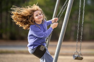 Heyecanlı çocuk eğleniyor. Çocuk bahçesinde mutlu bir çocuk. Havada sallanan tasasız çocuk. Mutlu çocuklar dışarıda oynuyor. Genç çocuk heyecanla sallanıyor. Dışarıdaki oyuncu çocuk. Komik çocuk yüzü.