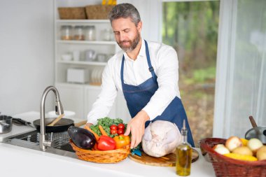 Mutfakta sebze pişirmek. Önlüklü şef modern mutfakta sağlıklı yemek hazırlıyor. Mutfakta sebzeli yemek. Aşçı evde sebzelerle kahvaltı hazırlar.