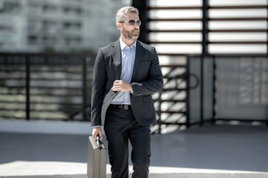 40 'lı yılların iş adamı bir evrak çantasıyla dışarıda dolaşıyor. İş adamı hareket halinde. Takım elbiseli olgun bir avukat. Çantası olan zengin bir iş adamı. Orta yaşlı iş adamı işe gidiyor. Yakışıklı avukat.