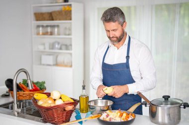 Şef mutfakta sebze pişiriyor. Önlüklü bir adam hammaddeyle sağlıklı bir yemek hazırlar. Sebzeli yemek. Akşam yemeği için taze sebzeli şef. Aşçı sebzelerle kahvaltı hazırlar.