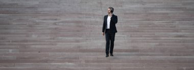 İşadamı merdivenlerden yukarı çıktı. Profesyonel büyüme ve başarıya doğru adım atan bir adam. Adım adım kariyer başarısına doğru. İşadamı merdivenleri çıkıyor. İş hedeflerine adım at