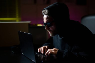 Şifreli para hackleme. Şifreli para için hackleme. Kripto para birimi hacklemesi. Kapüşonlu, karanlık gece temalı bir bilgisayar korsanı. Dijital veri güvenliği kavramı. Hackerlar saldırır. Siber güvenlik, internet suçları