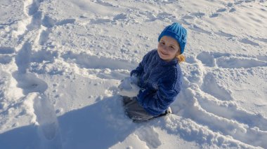 Karda oynayan bir çocuk. Çocuklar karlı kış parkında oynuyorlar. Kar taneleri yağarken kış eğlencesi. Çocuk soğuk kış havasının tadını çıkarıyor. Çocuklar kışın açık havada portre yaparlar. Kardaki çocuk.