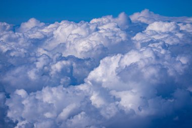 Sakin bulutlarla kaplı mavi bir gökyüzü. Parlak mavi gökyüzü arkaplanı. Bulutlu beyaz bulutlar. Sakin bir yaz gününde gökyüzü bulutlu. Bulutların arasından geçen güneş ışığı. Yumuşak bulutlu bahar gökyüzü