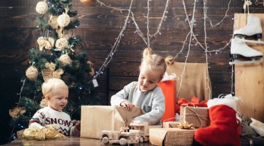 Mutlu çocuklar. Neşeli şirin çocuk Noel hediyesini açıyor. Ahşap arka planda Noel hediyesi olan mutlu bir çocuk. Noel çocukları. Neşeli bebek evde Noel 'de kameraya bakıyor.