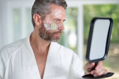 İspanyol erkek dermatoloji onaylı cilt bakımı yapıyor. Milenyum adamı doğal kozmetiklerle güzel bir yüz rutini yapıyor. Çekici erkek nemlendirici sürüyor.