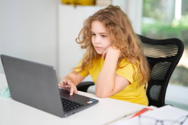 Kid studying mathematics on laptop during e-learning session. Student streaming online lesson. Child doing schoolwork in home classroom interior. Online education and digital study
