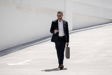 Açık hava iş portresi. Dışarıda yürüyen bir iş adamı. Başarılı lider hareket halinde. Çantalı takım elbiseli adam. İşadamı işe gidiyor. Çantası olan bir iş adamı. İş başarısı