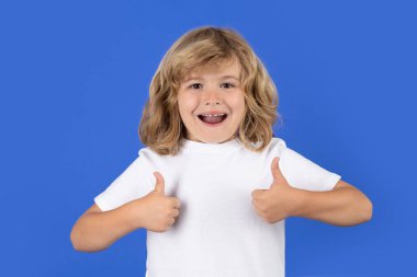 Heyecanlı çocuk, stüdyo izole edilmiş arka planda onay veriyor. Çocuk portresi başparmak işareti yapıyor.