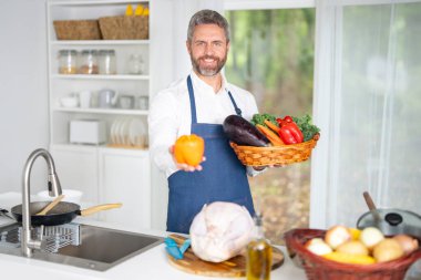 Mutfakta sebze doğruyor. Önlüklü şef, çiğ malzemeyle sağlıklı bir yemek hazırlar. Sebzeli yemek. Akşam yemeği için taze sebzelerle yemek pişir. Aşçı sebzelerle kahvaltı hazırlar.