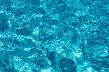 Mavi havuz suyu arka planı. Bulanık şeffaf, durgun su yüzeyi dokusu. Güneş ışığı altında su dalgaları kopyalama alanı ile