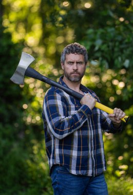 Kareli gömlekli yakışıklı ya da oduncu balta tutuyor. Oduncu ya da oduncu. Erkeklik kavramı. Vahşi, güçlü, çekici bir adam ormanda baltayla odun kesiyor. Ormanda baltası olan oduncu.
