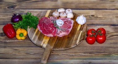 Raw beef steak on wooden board with ingredients. Fresh sliced meat prepared for cooking. Beef fillet with rosemary and pepper. Raw beefsteak. Fresh meat slice ready for grill or barbecue
