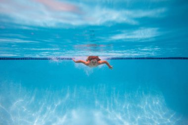 Yüzme havuzundaki su altı çocuğu. Havuzda suyun altında yüzen tatlı çocuk. Su oyunları, çocuklar için sağlıklı açık hava sporları.