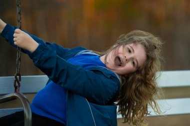 Çocuk dışarıda salıncakta sallanıyor. Dışarıda mutlu bir çocuk var. Çocuk parkında. Özgürlük portresi çocuk. Bahçede sallanan gülümseyen bir çocuk. Mutlu çocukluk