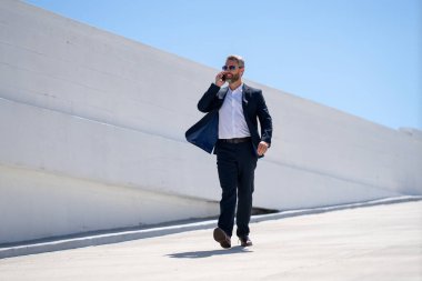 İş adamı dışarıda telefonla konuşuyor. Telefon görüşmesinde başarılı bir adam. İş adamı dışarıyı arıyor. Cep telefonu olan yakışıklı bir iş adamı. Cep telefonundan konuşan kendine güvenen bir adam. Çevrim içi iş