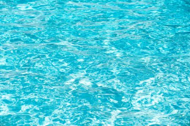 Mavi havuz suyu arka planı. Bulanık şeffaf, durgun su yüzeyi dokusu. Güneş ışığı altında su dalgaları kopyalama alanı ile