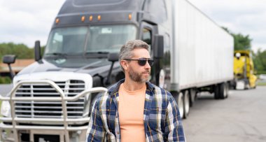 Kamyon şoförü. Kamyon şoförü büyük bir tırın yanında duruyor. Kargo taşımacılığı ve teslimat işi için kamyon. Kamyon işçisi konsepti. Şoförlü kargo karavanı