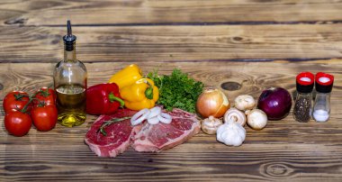 Raw meat on wooden table. Fresh meat slice ready for grill or barbecue. Ingredient for recipe with meat. Raw beef steak preparation with vegetables. Beef piece on board. Cooking raw meat