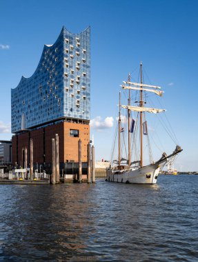 Elbphilharmonie cephesi ve uzun gemi direkleri. Hamburg Almanya 'sının turist ve seyahat ikonu. Hamburg 'da yelkenli ve mimariyle şehir manzarası. Elbe Filarmoni Salonu