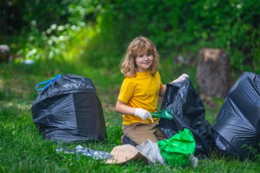 Lastik eldivenli çocuk çöp torbasıyla ormandaki çöpleri temizliyor. Eko, çevre koruma. Kirliliği geri dönüştür. Çocuk çöp ve plastik çöp topluyor. Ortamı kaydet
