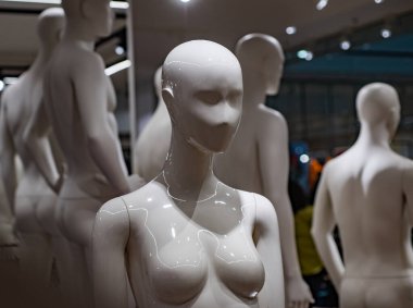Parlak butikte bir grup manken. Perakende sanatı olarak soyut insan figürleri. Modern moda kompozisyonu. Dengeli ışıklandırma altında pürüzsüz formlar. Dükkanda en az stil kurulumu