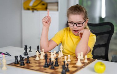 Çocuk satranç düşünüyor. Masada satranç oynayan düşünceli bir çocuk. Akıllı çocuk satrançla mantık öğreniyor. Sınıfta satranç oynayan öğrenciler. Çocuk ve satranç tahtasıyla sıcak bir ev sahnesi