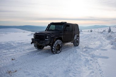01.02.2021, Karpatlar. Gün batımında kar içinde off-road SUV. 4x4 jipli bir kış seferi. Kış doğasında zorlu bir off-road gezisi. Off-road arabalı dağ yolu. Kar yolunda macera gezisi
