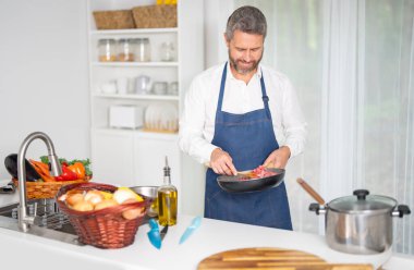 Şef mutfakta sebze doğruyor. Önlüklü şef, çiğ malzemeyle sağlıklı bir yemek hazırlar. Sebzeli yemek. Akşam yemeği için taze sebzeli şef. Şef sebzelerle kahvaltı hazırlar.