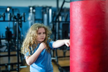 Eğitimdeki boksör çocuk. Çocuk boksörü egzersizi. Sportif çocuk boks torbasına vuruyor. Çocuk kickboks ve boks çalışıyor. Aktif çocuk dövüşçüsü portresi. Spor salonunda boks egzersizi. Çocuklar için spor ve güç